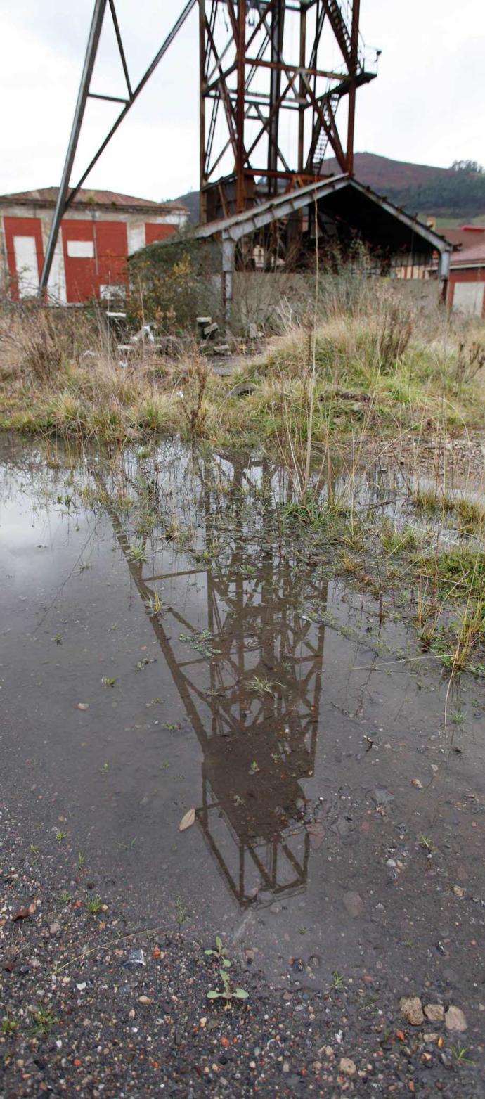 Un castillete del pozo n�mero 1 de la mina reflejado en un charco de la explotaci�n. [Foto: �ngel Gonz�lez]